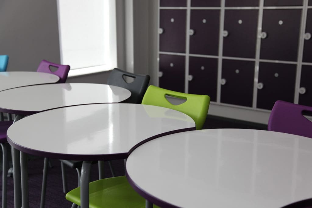 White classroom tables with chairs of different colours